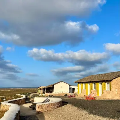 a building with yellow doors and a sky with clouds at Spinguera Ecolodge in Espingueira