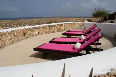 a row of pink chaise lounges on a beach at Spinguera Ecolodge in Espingueira