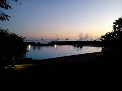 a sunset over a swimming pool with boats in the water at Porto Antigo - Charming & peaceful apartment overlooking pool and sea in Santa Maria