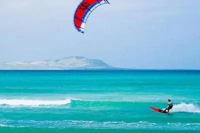 a person on a surfboard in the ocean with a kite at Porto Antigo - Charming & peaceful apartment overlooking pool and sea in Santa Maria