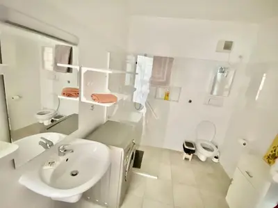 a white bathroom with a sink and a toilet at Porto Antigo - Charming & peaceful apartment overlooking pool and sea in Santa Maria