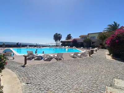 a swimming pool with chairs and the ocean in the background at Porto Antigo - Charming & peaceful apartment overlooking pool and sea in Santa Maria