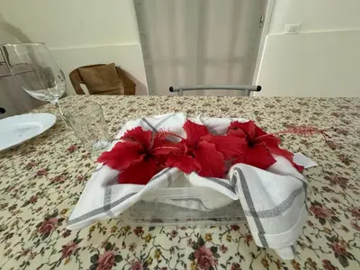 a table with a white and red napkin and flowers on it at Vista Do Mar Studio Praia Cabral in Sal Rei