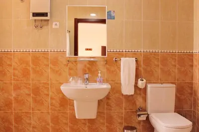 a bathroom with a sink and a toilet and a mirror at Hotel LIVVO Don Paco in Mindelo