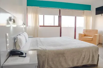 a white room with a bed and a chair at Hotel LIVVO Don Paco in Mindelo