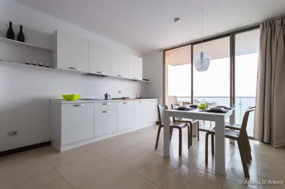 a kitchen with white cabinets and a table with chairs at Apartamento Las Rochas in Mindelo