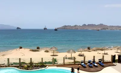 a view of a beach with chairs and the ocean at Apartamento Las Rochas in Mindelo