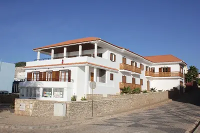 a large white house with a stone wall at Hotel Casa Evora - luxury and beach front in Vila do Maio