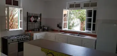 a kitchen with a stove and a sink and two windows at Surf House Hostel in Santa Maria