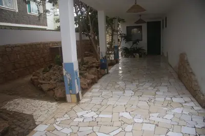 a hallway with a stone floor and a pillar at Surf House Hostel in Santa Maria