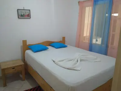 a bedroom with a bed with blue pillows and a window at Pensão Domingas in São Filipe