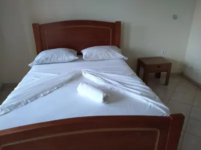 a bed with white sheets and two pillows on it at Pensão Domingas in São Filipe