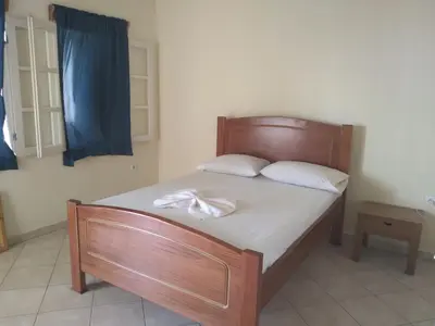 a bed with a wooden frame with a towel on it at Pensão Domingas in São Filipe