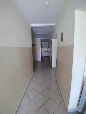 an empty hallway with white walls and a tile floor at Pensão Domingas in São Filipe