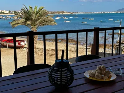 a table with a plate of food on a balcony with the beach at Casa Tud Dret - By Bobbywashere in Sal Rei