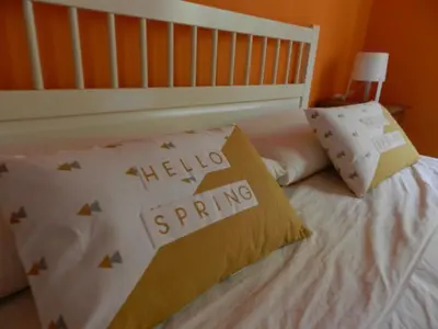 a bed with a hello spring pillow on it at La Residencia in Mindelo