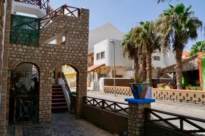 a brick building with a gate and a palm tree at Pensão Alcinda Bettencourt 50 meters to the Beachfront in Santa Maria