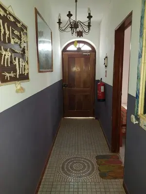 a hallway with a wooden door and a tile floor at Pensão Alcinda Bettencourt 50 meters to the Beachfront in Santa Maria