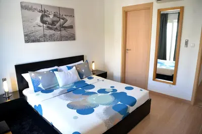 a bedroom with a large bed with blue and white sheets at Guesthouse Le Châtelain in Santa Maria