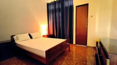 a bedroom with a bed and a table and a door at Residencial Amarante in Mindelo