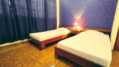 a hotel room with two beds and a lamp at Residencial Amarante in Mindelo