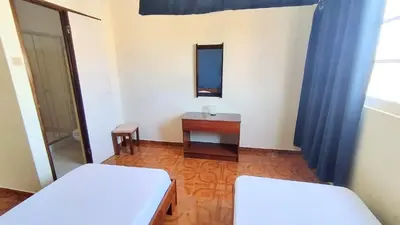 a room with two beds and a table and a mirror at Residencial Amarante in Mindelo