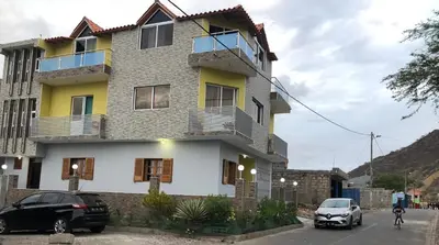 a building with two cars parked in front of it at Dunas De Areia Preta in Ribeira da Prata