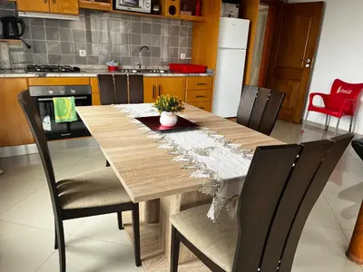 a kitchen with a wooden table with chairs and a kitchen with a refrigerator at Dunas De Areia Preta in Ribeira da Prata