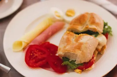 a plate of food with a sandwich and tomatoes at Dunas De Areia Preta in Ribeira da Prata