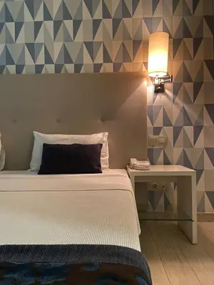 a bedroom with a bed and a table with a lamp at Ouril Hotel Julia in Santa Maria