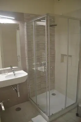 a bathroom with a glass shower and a sink at Ouril Hotel Julia in Santa Maria