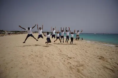 a group of people jumping on the beach at Halos Casa Resort in Santa Maria