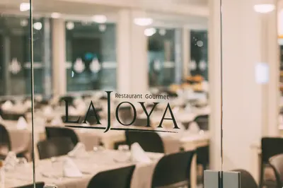 a restaurant with white tables and chairs and a restaurant sign at Halos Casa Resort in Santa Maria