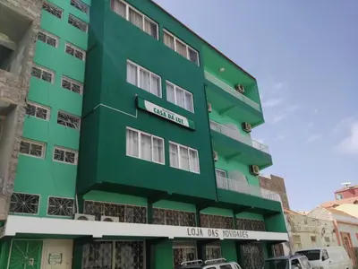 a green building with cars parked in front of it at Residencial Casa da Luz in Mindelo