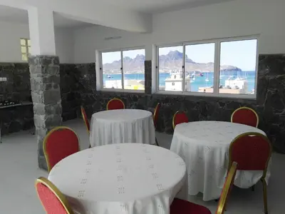 two tables and chairs in a room with windows at Residencial Casa da Luz in Mindelo