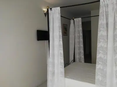 a bedroom with a bed with white curtains and a mirror at Residencial Casa da Luz in Mindelo