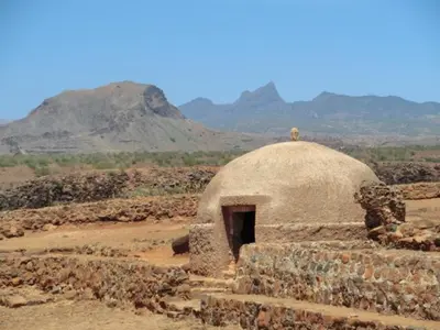 a small building in a field with mountains in the background at Aparthotel Praiano in Praia