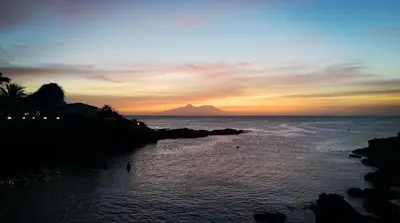 a sunset over the ocean with a mountain in the background at Casa Tabanka Apartment in Tarrafal