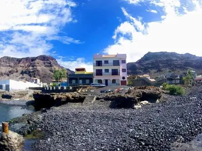 a building on a rocky area with a mountain at bed & breakfast Regina in Tarrafal