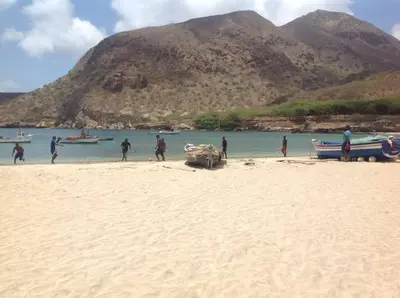 a group of people standing on a beach with boats at Casa Cabral : Big Apartment next to the beach in Tarrafal