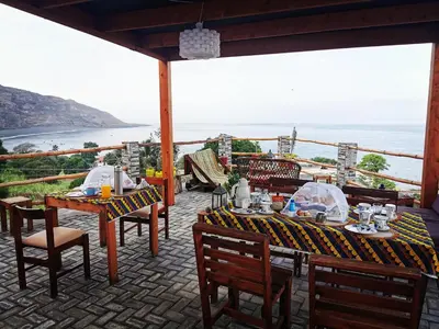 a table and chairs on a patio with a view of the ocean at Kaza Ladera in Seladinha