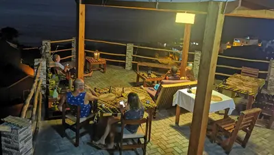 a group of people sitting at a table on a balcony at Kaza Ladera in Seladinha