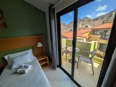 a bedroom with a bed and a view of a balcony at Hotel Belvedere Mindelo, Cabo Verde in Mindelo