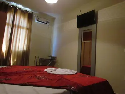 a bedroom with a bed with a red blanket and a mirror at Residêncial Carlos Carvalho in Praia