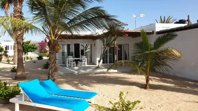 a blue chair and palm trees in front of a house at Beachhaus Praia de Chaves in Cabeçadas