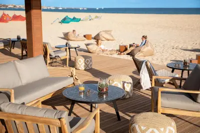 a beach with tables and chairs and people on the beach at ROBINSON Cabo Verde - Adults only in Santa Maria