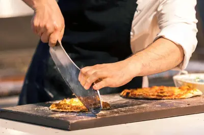 a person cooking pizzas on a grill at ROBINSON Cabo Verde - Adults only in Santa Maria