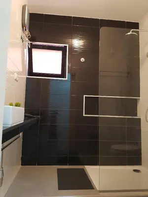 a bathroom with a glass shower with a window at Casa Io - Djeu in Mindelo