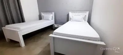 two beds in a small room with white furniture at Cantinho C - Alojamento Complementar in Praia
