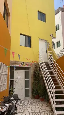 a yellow building with a staircase leading to a garage at Cantinho C - Alojamento Complementar in Praia